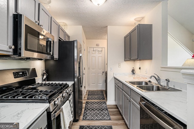 855 Lakeside Cir, Covington, GA 30016 - kitchen with appliances with stainless steel finishes, gray cabinetry, a sink, a textured ceiling, and light wood-style floors