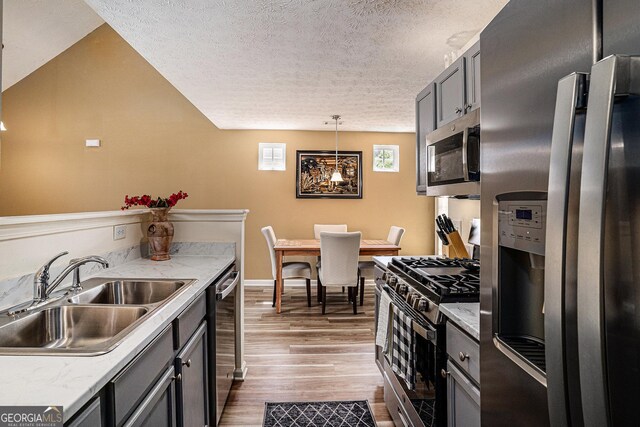 855 Lakeside Cir, Covington, GA 30016 - kitchen featuring stainless steel appliances, a sink, wood finished floors, a textured ceiling, and light countertops