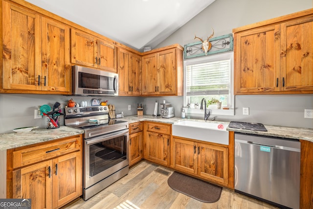 751 Hawkins Rd, Homer, GA 30547 - kitchen featuring stainless steel appliances, a sink, lofted ceiling, light wood-style floors, and brown cabinets