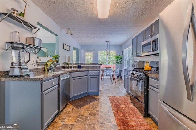 4348 Tillage Path, Douglasville, GA 30135 - kitchen featuring appliances with stainless steel finishes, stone finish floors, dark countertops, gray cabinets, and a peninsula