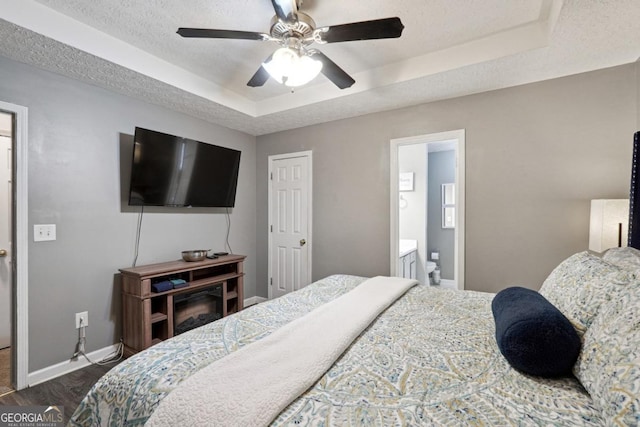 11529 Vinea Ln, Hampton, GA 30228 - bedroom with a tray ceiling, baseboards, a textured ceiling, ceiling fan, and ensuite bathroom