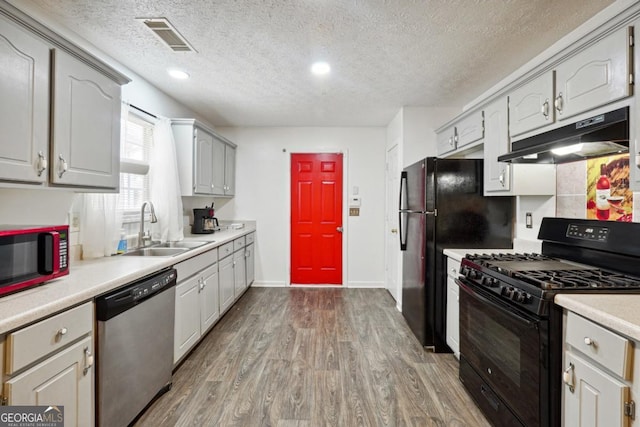 11529 Vinea Ln, Hampton, GA 30228 - kitchen with black appliances, a sink, under cabinet range hood, wood finished floors, and a textured ceiling