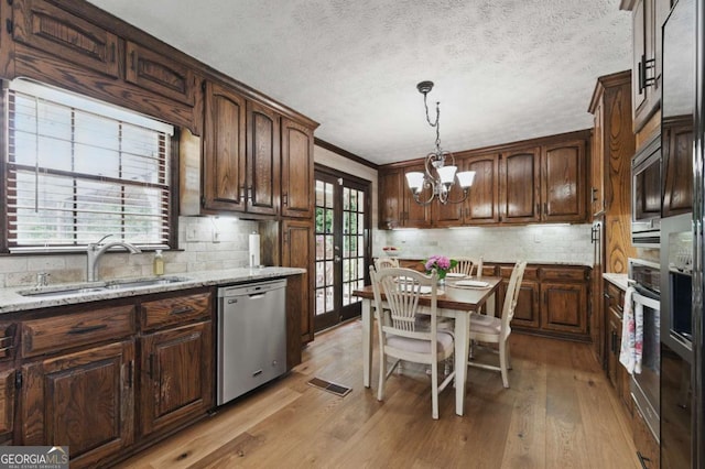 4205 Jeri Lynn Ct, Tucker, GA 30084 - kitchen featuring appliances with stainless steel finishes, a sink, a chandelier, light wood finished floors, and decorative backsplash