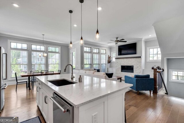 3108 Huntington Pl, Milton, GA 30004 - kitchen featuring a sink, stainless steel appliances, ceiling fan, a fireplace, and light wood-style flooring