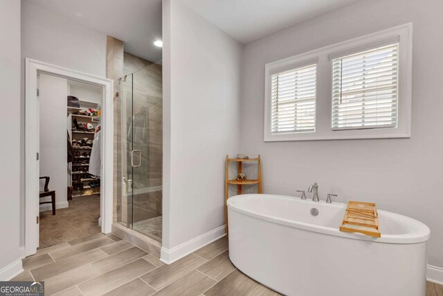 3108 Huntington Pl, Milton, GA 30004 - full bathroom featuring baseboards, a spacious closet, a shower stall, a soaking tub, and wood tiled floors