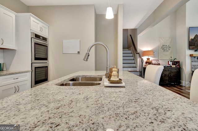 234 Thyme Leaf Way, Locust Grove, GA 30248 - kitchen featuring stainless steel double oven, a sink, white cabinets, light stone countertops, and pendant lighting