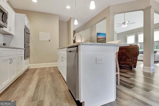 234 Thyme Leaf Way, Locust Grove, GA 30248 - kitchen with stainless steel appliances, a ceiling fan, a kitchen breakfast bar, light wood-style floors, and light stone counters
