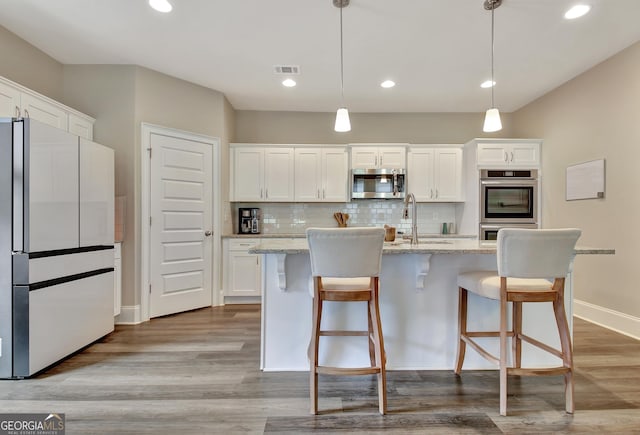 234 Thyme Leaf Way, Locust Grove, GA 30248 - kitchen featuring freestanding refrigerator, stainless steel microwave, white cabinets, a sink, and a kitchen island with sink
