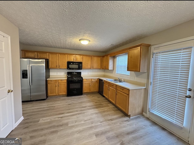 3292 Shady Valley Ct, Loganville, GA 30052 - kitchen with black appliances, light countertops, light wood-style floors, a textured ceiling, and brown cabinets