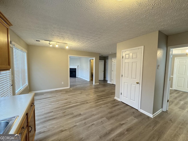 3292 Shady Valley Ct, Loganville, GA 30052 - unfurnished living room featuring light wood-type flooring, a textured ceiling, and rail lighting