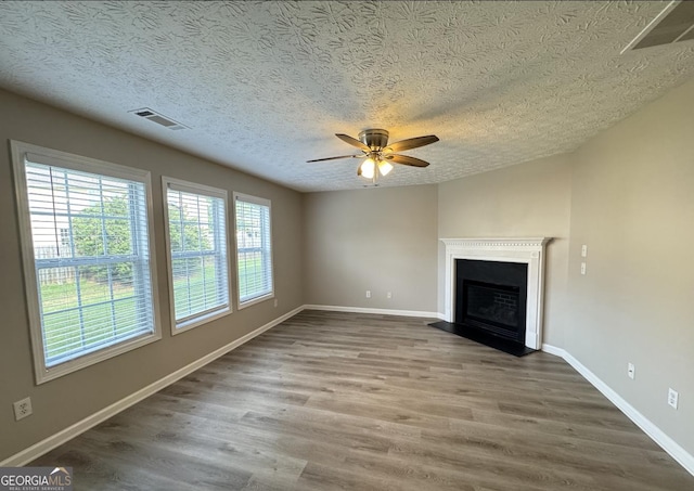 3292 Shady Valley Ct, Loganville, GA 30052 - unfurnished living room featuring a textured ceiling, plenty of natural light, ceiling fan, wood finished floors, and a fireplace with raised hearth