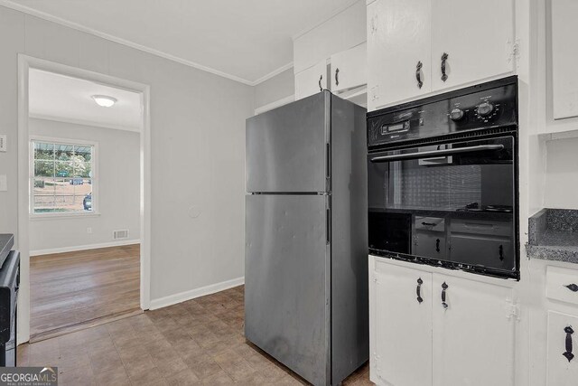 2261 Star Mist Dr SW, Atlanta, GA 30311 - kitchen with freestanding refrigerator, oven, crown molding, white cabinetry, and dark countertops