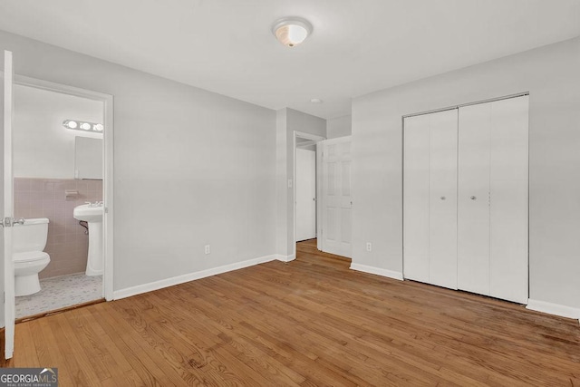 2261 Star Mist Dr SW, Atlanta, GA 30311 - unfurnished bedroom featuring wood finished floors, a closet, ensuite bathroom, and tile walls