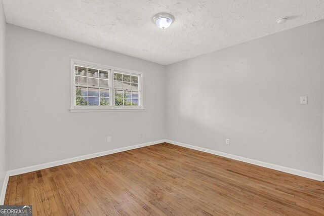 2261 Star Mist Dr SW, Atlanta, GA 30311 - empty room with a textured ceiling, baseboards, wood finished floors, and a smoke detector