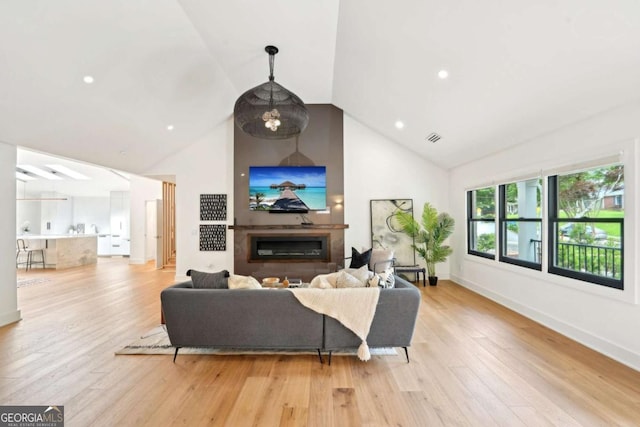 1815 Coventry Rd, Decatur, GA 30030 - living room featuring high vaulted ceiling, light wood-type flooring, a glass covered fireplace, baseboards, and recessed lighting