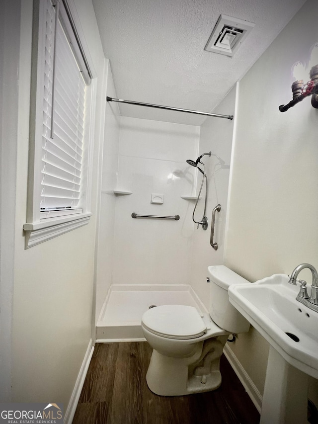 108 Plum St, Dublin, GA 31021 - full bath with wood finished floors, a shower stall, toilet, baseboards, and a textured ceiling