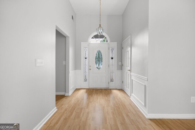 4801 Devonhurst Way, Powder Springs, GA 30127 - foyer entrance with light wood finished floors, a towering ceiling, wainscoting, a chandelier, and a decorative wall