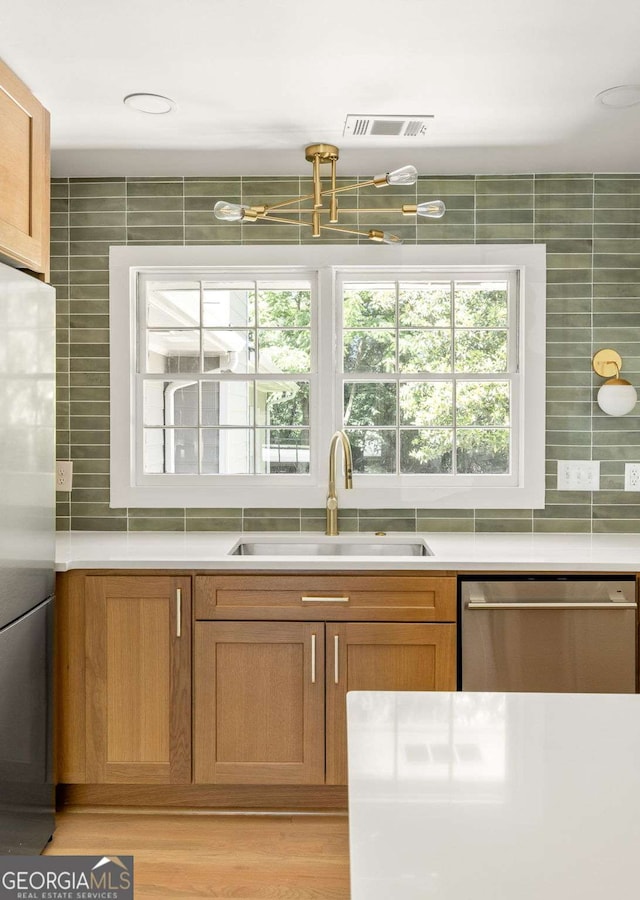 762 Rockbridge Rd NW, Lilburn, GA 30047 - kitchen featuring appliances with stainless steel finishes, a sink, backsplash, light countertops, and brown cabinetry
