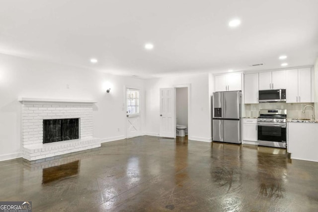 762 Rockbridge Rd NW, Lilburn, GA 30047 - unfurnished living room with recessed lighting, a sink, a brick fireplace, concrete floors, and baseboards