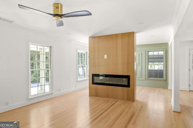 762 Rockbridge Rd NW, Lilburn, GA 30047 - unfurnished living room with light wood-style floors, crown molding, ceiling fan, a glass covered fireplace, and plenty of natural light
