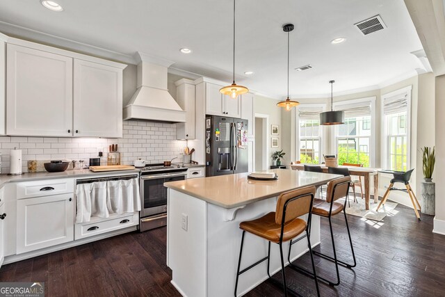 90 Middle St, Senoia, GA 30276 - kitchen with appliances with stainless steel finishes, custom exhaust hood, tasteful backsplash, white cabinets, and ornamental molding