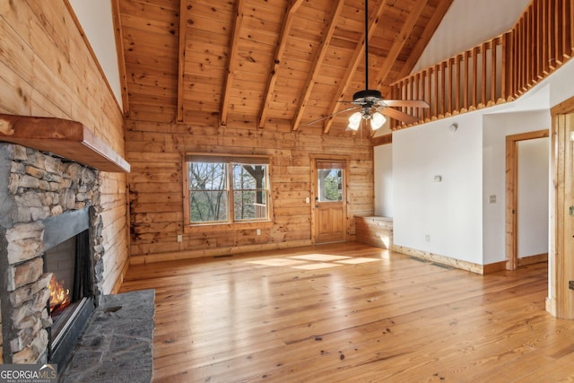 435 Ranch Mountan Dr, Dahlonega, GA 30533 - unfurnished living room featuring wood ceiling with exposed beams, high vaulted ceiling, a stone fireplace, wood walls, and wood-type flooring