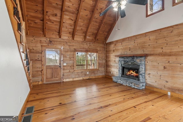 435 Ranch Mountan Dr, Dahlonega, GA 30533 - unfurnished living room featuring wood-type flooring, wood ceiling with exposed beams, a ceiling fan, a stone fireplace, and wood walls