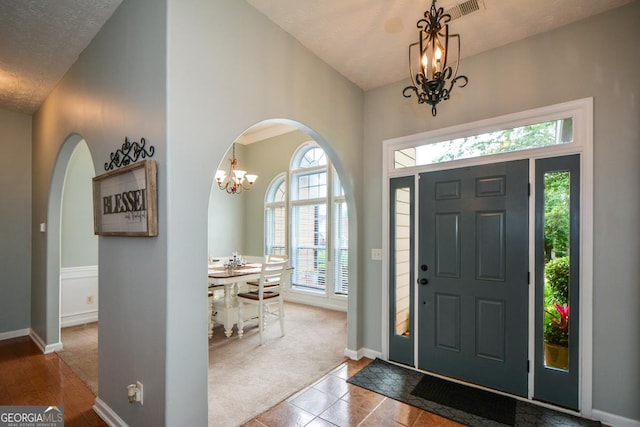 9013 Aldbury Dr, Locust Grove, GA 30248 - carpeted entryway with a chandelier, arched walkways, baseboards, and tile patterned floors