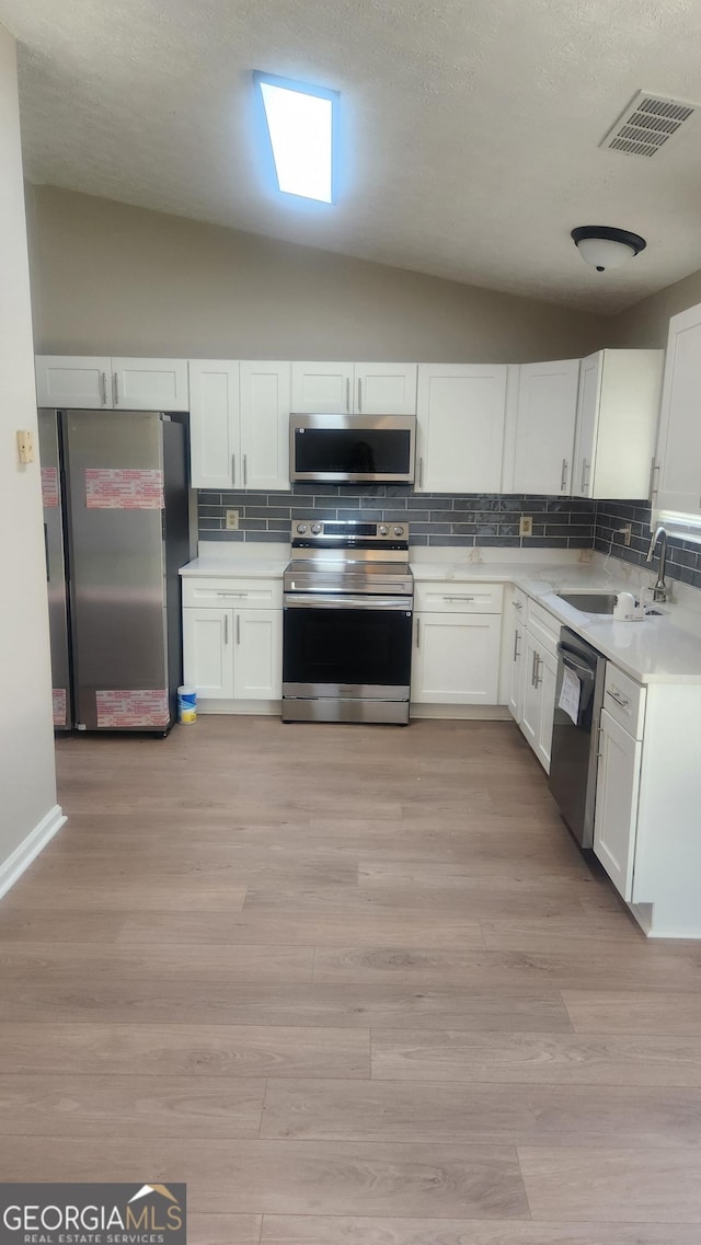 6120 Raleigh Oaks Ct, Lithonia, GA 30058 - kitchen featuring appliances with stainless steel finishes, a sink, backsplash, light countertops, and vaulted ceiling