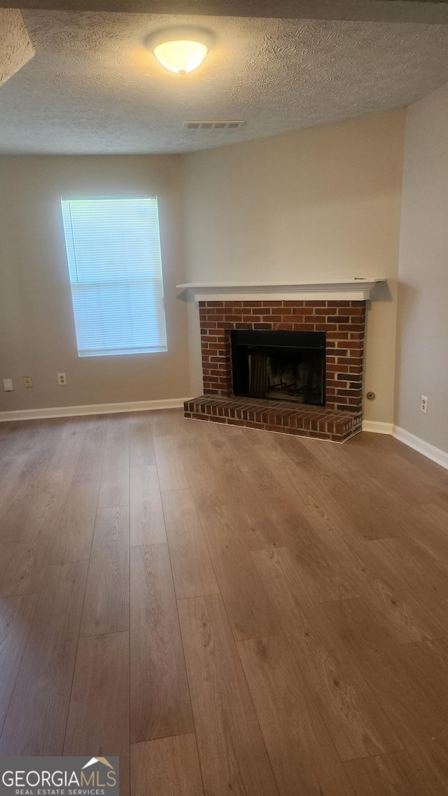 6120 Raleigh Oaks Ct, Lithonia, GA 30058 - unfurnished living room featuring a fireplace, wood finished floors, a textured ceiling, and baseboards