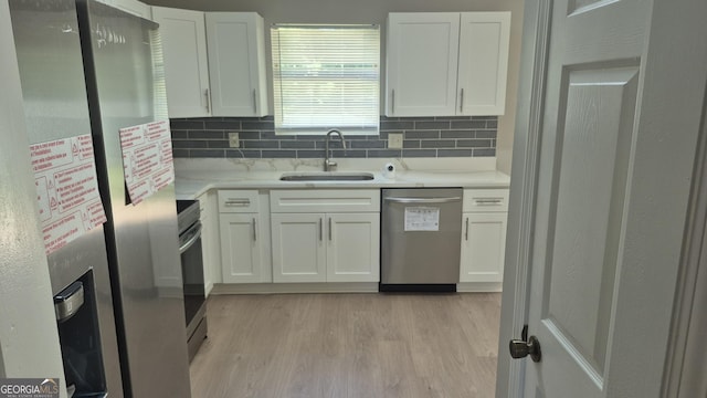 6120 Raleigh Oaks Ct, Lithonia, GA 30058 - kitchen with appliances with stainless steel finishes, a sink, white cabinets, light countertops, and decorative backsplash