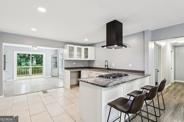 6072 Holiday Blvd, Forest Park, GA 30297 - kitchen with island range hood, stainless steel gas cooktop, a sink, a peninsula, and white cabinets
