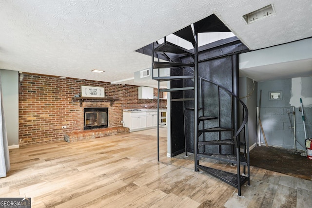 6072 Holiday Blvd, Forest Park, GA 30297 - stairway featuring a textured ceiling, wood finished floors, brick wall, and a brick fireplace