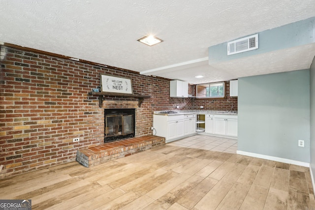 6072 Holiday Blvd, Forest Park, GA 30297 - unfurnished living room featuring light wood-style floors, a textured ceiling, baseboards, and a fireplace