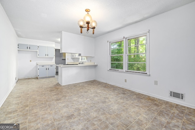 136 Briarwood Dr, Toccoa, GA 30577 - kitchen with a chandelier, a peninsula, a textured ceiling, light countertops, and baseboards