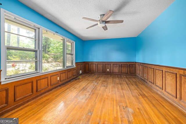 136 Briarwood Dr, Toccoa, GA 30577 - unfurnished room featuring a textured ceiling, light wood-style floors, a ceiling fan, and a wainscoted wall