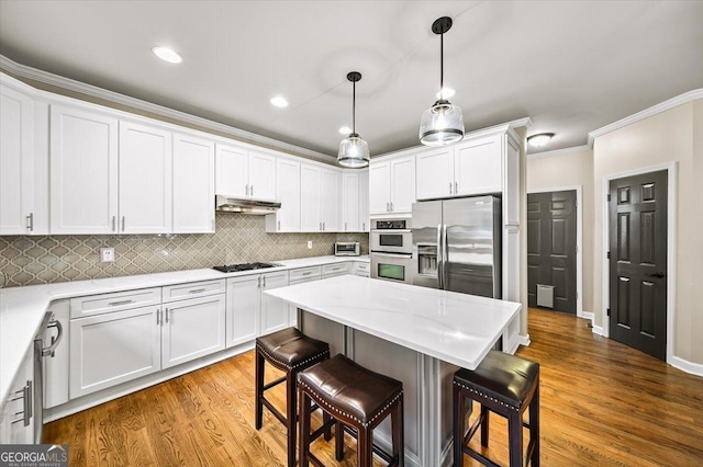 161 Highgrove Dr, Suwanee, GA 30024 - kitchen with appliances with stainless steel finishes, under cabinet range hood, a kitchen bar, ornamental molding, and white cabinets