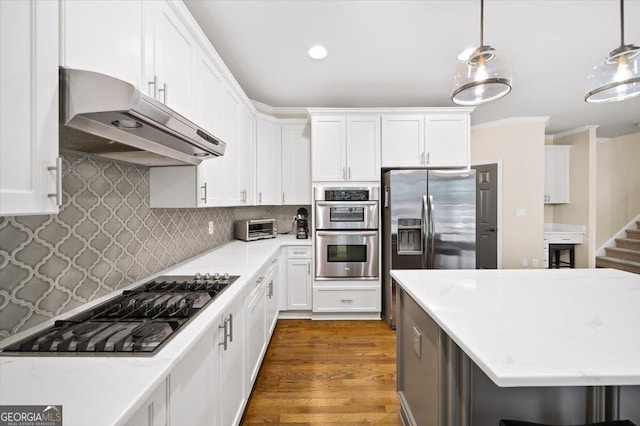 161 Highgrove Dr, Suwanee, GA 30024 - kitchen featuring under cabinet range hood, appliances with stainless steel finishes, white cabinets, wood finished floors, and crown molding
