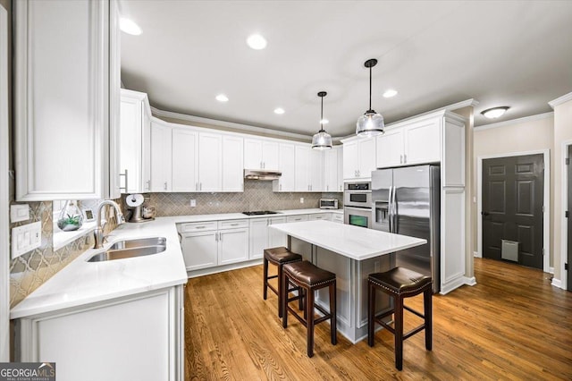 161 Highgrove Dr, Suwanee, GA 30024 - kitchen with stainless steel appliances, a sink, under cabinet range hood, a breakfast bar area, and ornamental molding
