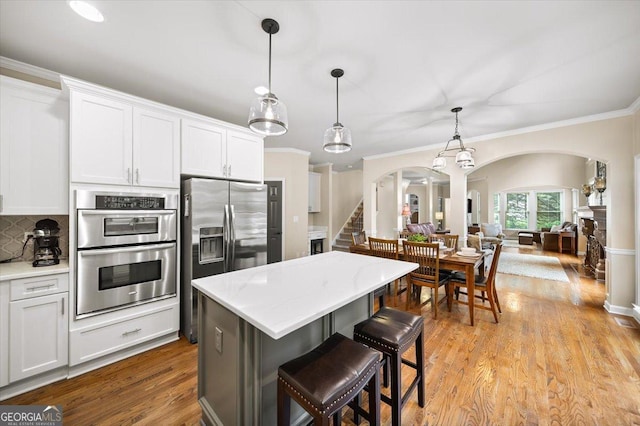 161 Highgrove Dr, Suwanee, GA 30024 - kitchen featuring arched walkways, stainless steel appliances, ornamental molding, backsplash, and light countertops