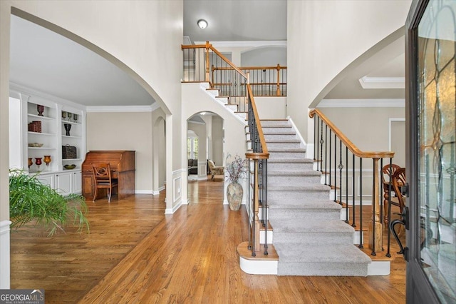 161 Highgrove Dr, Suwanee, GA 30024 - foyer entrance featuring arched walkways, wood finished floors, stairs, a high ceiling, and ornamental molding
