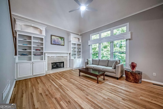 1325 Starboard Way, Cumming, GA 30041 - living area featuring ceiling fan, light wood-type flooring, crown molding, a tiled fireplace, and baseboards