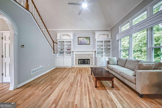 1325 Starboard Way, Cumming, GA 30041 - living area with a ceiling fan, arched walkways, light wood finished floors, high vaulted ceiling, and a tile fireplace