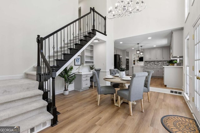 5706 Brookstone Walk NW, Acworth, GA 30101 - dining space featuring a chandelier, light wood finished floors, stairs, a high ceiling, and recessed lighting