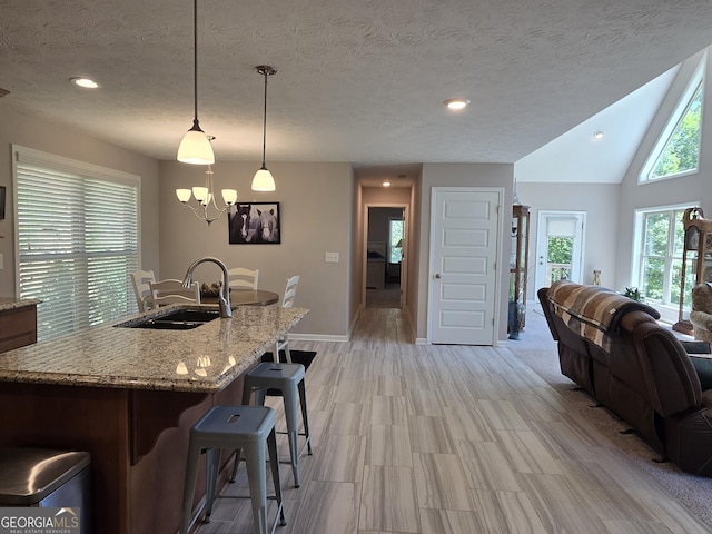 1356 Woodbrier, Sautee Nacoochee, GA 30571 - kitchen featuring a sink, a kitchen breakfast bar, light stone counters, a chandelier, and decorative light fixtures