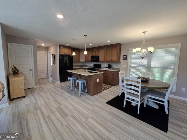 1356 Woodbrier, Sautee Nacoochee, GA 30571 - kitchen featuring black appliances, a kitchen island with sink, a chandelier, a sink, and a breakfast bar
