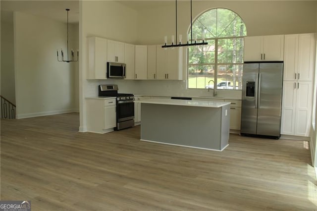 4220 Glad Morning Dr, College Park, GA 30349 - kitchen featuring stainless steel appliances, white cabinets, light countertops, light wood finished floors, and a towering ceiling