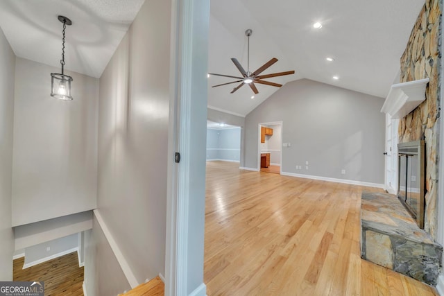 112 White Oak Cir, Dublin, GA 31021 - unfurnished living room featuring ceiling fan, vaulted ceiling, a stone fireplace, wood finished floors, and baseboards