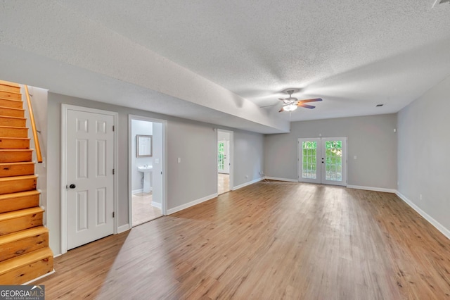 112 White Oak Cir, Dublin, GA 31021 - unfurnished living room with ceiling fan, stairs, light wood-style flooring, a textured ceiling, and baseboards