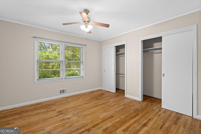 416 S Carroll Rd, Villa Rica, GA 30180 - unfurnished bedroom with two closets, ornamental molding, light wood-style flooring, baseboards, and ceiling fan